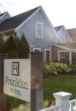 Franklin Hotel sign in front of sunny lawn with chairs and garden