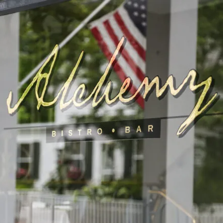 Alchemy bistro and bar sign with American flag outdoor seating