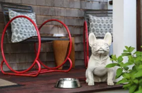 Patio seating with red chairs and a white bulldog statue holding a dog bowl