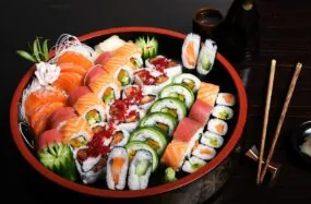 Large platter of assorted sushi rolls with chopsticks on the side